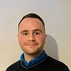 Lächelnder ALDI SÜD Auszubildener vor heller Wand