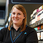 ALDI SÜD Mitarbeiterin im Gang einer Filiale lächelt freundlich in die Kamera