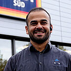 ALDI SÜD Mitarbeiter im Außenbereich der Filiale lächelt freundlich in die Kamera