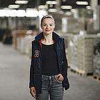 ALDI SÜD Auszubildene steht im Lager der Logistik, hat eine Hand in der Tasche und schaut freundlich in die Kamera