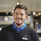 ALDI SÜD Verkäufer in der Filiale lächelt freundlich in die Kamera