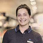 ALDI SÜD stellvertretende Filialleiterin lächelt freundlich in die Kamera vor dem Verkaufsregal