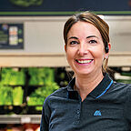 ALDI SÜD Mitarbeiterin in der Obst- und Gemüseabteilung einer Filiale lächelt freundlich in die Kamera
