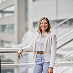 ALDI SÜD Mitarbeiterin der Verwaltung lehnt am Treppengeländer und blickt lachend in die Kamera