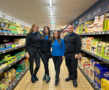 Vier ALDI SÜD Auszubildene posieren lächelnd in einem Gang der Filiale